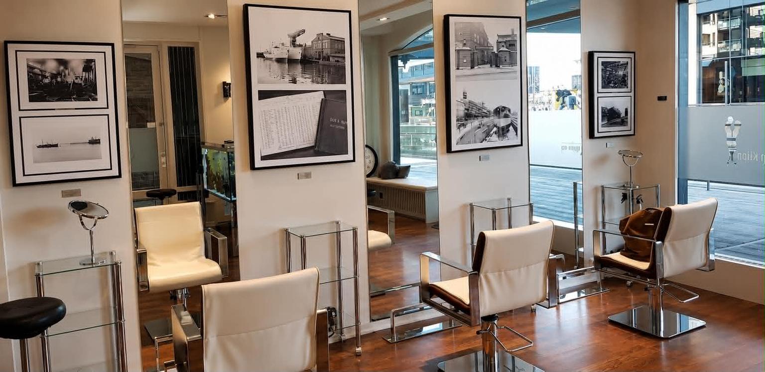 Innrammede svart-hvitt-fotografier fra Akers Mekaniske Verksted som hang på veggen mellom stylingstolene på salongen på Aker Brygge